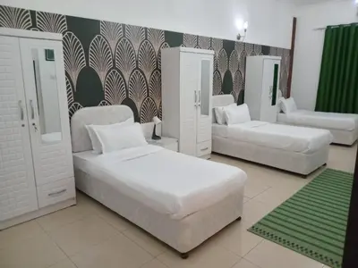 a bedroom with two beds and two chairs at AlWasl Guesthouse by PHM in Dubai