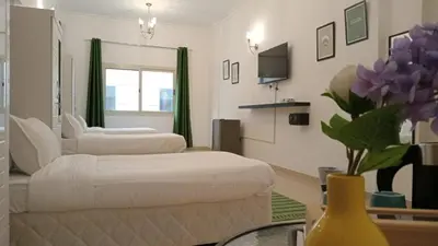 a room with two beds and a vase with purple flowers at AlWasl Guesthouse by PHM in Dubai