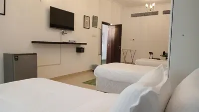 a hotel room with two beds and a flat screen tv at AlWasl Guesthouse by PHM in Dubai