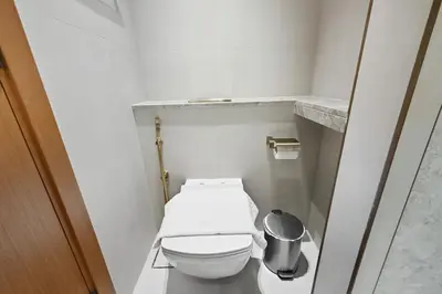 a small bathroom with a toilet and a trash can at Golden Stays - Private Pool Modern 2BR Oasis in JVC in Dubai