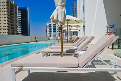 a row of chaise lounge chairs next to a swimming pool at Golden Stays - Private Pool Modern 2BR Oasis in JVC in Dubai