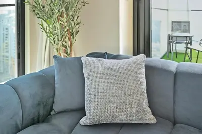 a pillow sitting on a blue couch in a living room at Golden Stays - Private Pool Modern 2BR Oasis in JVC in Dubai