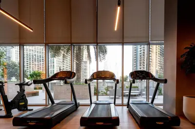 a row of treadmills in a gym with a large window at Forte 3BR Luxury PS5 Gaming Room Sleeps 9 in Dubai