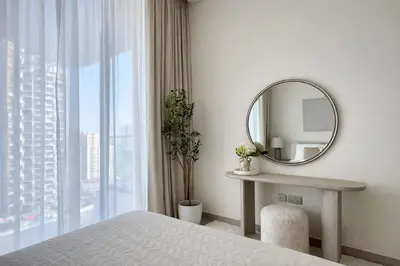 a white bedroom with a mirror and a window at Stylish Stay with Plunge Pool & Scenic Pool View in Dubai