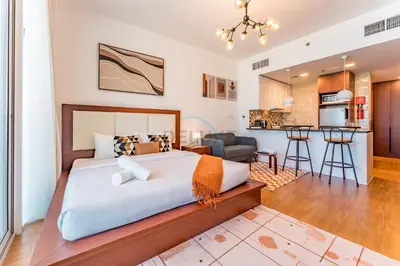 a bedroom with a large bed and a kitchen at Skyline Studio Overlooking the Community, Only a Few Steps from the Park, Al Jawhara Tower, Jumeirah Village Triangle by Deluxe Holiday Homes in Dubai