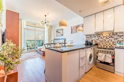a kitchen with a washer and dryer at Skyline Studio Overlooking the Community, Only a Few Steps from the Park, Al Jawhara Tower, Jumeirah Village Triangle by Deluxe Holiday Homes in Dubai