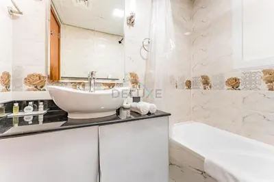 a white bathroom with a sink and a tub at Skyline Studio Overlooking the Community, Only a Few Steps from the Park, Al Jawhara Tower, Jumeirah Village Triangle by Deluxe Holiday Homes in Dubai