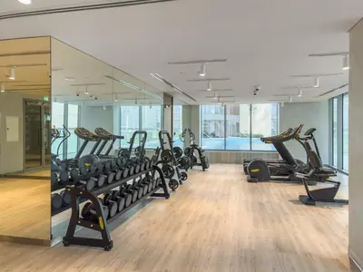 a gym with a row of treadmills and ellipticals at VayK - Elegant Canal-Front 1 BD in a Prime Location in Dubai