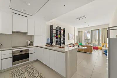 a kitchen with white cabinets and a living room at VayK - Elegant Canal-Front 1 BD in a Prime Location in Dubai