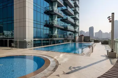 a swimming pool in front of a tall building at The Sky in Dubai