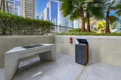 a trash can sitting next to a concrete bench at High Floor Unit with Canal View, A Minutes Drive to Dubai Mall - Zada Tower, Business Bay by Deluxe Holiday Homes in Dubai