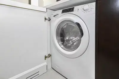 a white washing machine in a white laundry room at Cozy 1BR in Business Bay, 10 mins to Metro in Dubai