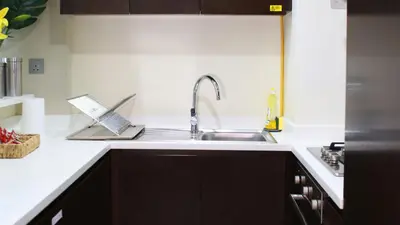 a kitchen with a sink and a laptop on the counter at Cozy 1BR in Business Bay, 10 mins to Metro in Dubai