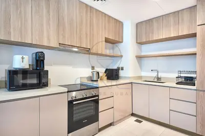 a kitchen with white cabinets and black appliances at Premium 2BR Apartment at Urban Oasis, Business Bay in Dubai