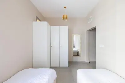 two beds in a white bedroom with a mirror at Bright 2BR Marina View with Balcony in Dubai
