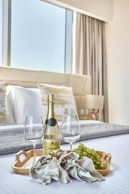 a bottle of champagne and wine glasses on a bed at Frank Porter - Adhara Star in Dubai