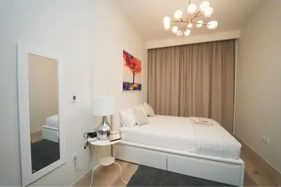 a white bedroom with a bed and a mirror at Luxury 2BR in Business Bay Close to Dubai Mall in Dubai