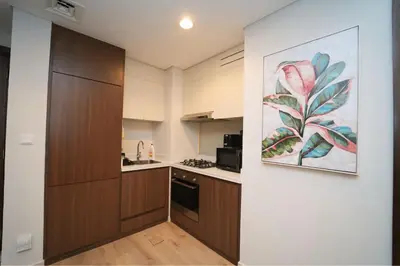 a kitchen with wooden cabinets and a painting on the wall at Luxury 2BR in Business Bay Close to Dubai Mall in Dubai