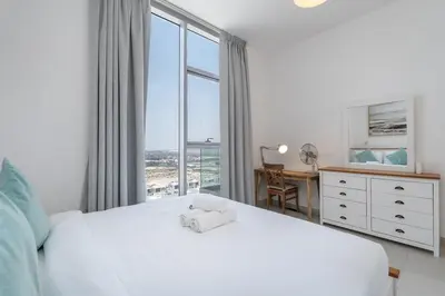 a bedroom with a white bed and a large window at StayShort - Cozy 2 Bedroom Retreat in Dubai South Close to Expo 2020 in Dubai Marina