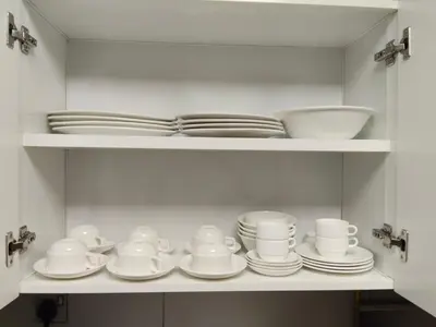 a white cabinet with plates and cups and dishes at Deluxe Apartments Near WTC and Sheikh Zayed in Dubai
