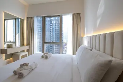 a bedroom with a large white bed with towels on it at Brand New 1BR - Burj View - Infinity Pool - Dubai Mall in Dubai