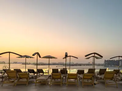 a group of chairs and umbrellas on a patio at Beachfront Luxury 1BR with Private Beach, Marina & Sea Views in Dubai