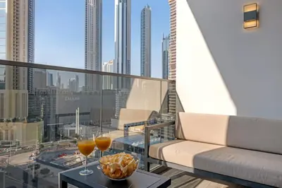 a balcony with a couch and two glasses of wine at Chic Studio Steps to Dubai Mall with Infinity Pool in Dubai