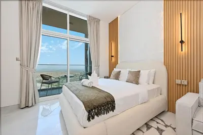 a bedroom with a bed and a view of the ocean at Luxury studio Near Miracle Garden with Gym & Pool in Dubai