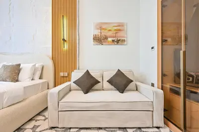a living room with a couch and a bed at Luxury studio Near Miracle Garden with Gym & Pool in Dubai