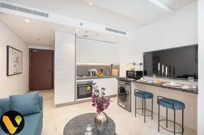 a kitchen and living room with a blue couch and a table at Vogue Downtown The Sterling by Omniyat, near Burj Khalifa and Dubai Mall, Studio Apartment with Balcony and Access to all Amenities in Dubai