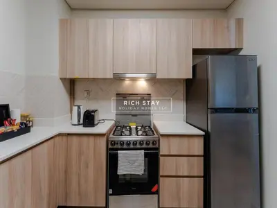 a kitchen with a stove and a refrigerator at Sway Retreat 1BR Apartment with Burj Khalifa View in Dubai