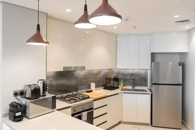 a kitchen with white cabinets and stainless steel appliances at Comfortable 2BR Near Downtown by Czechin in Dubai
