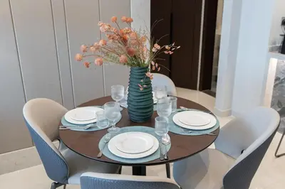 a table with plates and a vase with flowers on it at Comfortable 2BR Near Downtown by Czechin in Dubai