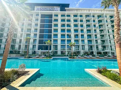 a hotel with a swimming pool in front of a building at WelHome - Urban Comfort Studio in JVC in Dubai