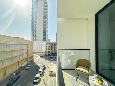 a chair sitting on a balcony overlooking a city at WelHome - Urban Comfort Studio in JVC in Dubai