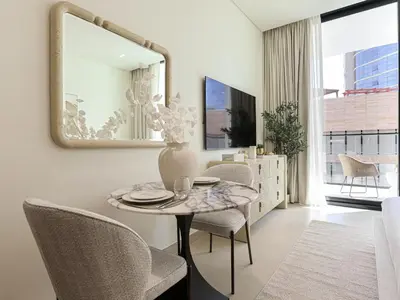 a dining room with a table and chairs and a mirror at WelHome - Urban Comfort Studio in JVC in Dubai