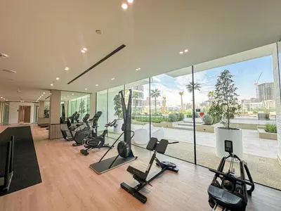 a gym with a lot of treadmills and exercise bikes at WelHome - Stylish Dubai Studio in Prime JVC Location in Dubai