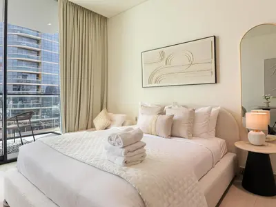 a bedroom with a large white bed and a balcony at WelHome - Stylish Dubai Studio in Prime JVC Location in Dubai