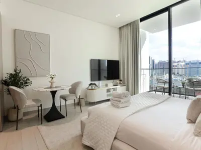 a bedroom with a bed and a table and a tv at WelHome - Stylish Dubai Studio in Prime JVC Location in Dubai