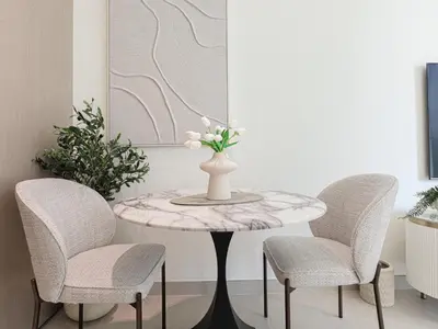 a table with two chairs and a vase with flowers on it at WelHome - Stylish Dubai Studio in Prime JVC Location in Dubai