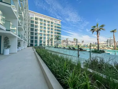 a building with a walkway next to a body of water at WelHome - Stylish Dubai Studio in Prime JVC Location in Dubai
