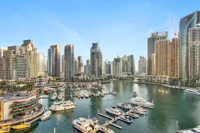 a river with boats in a city with tall buildings at Vogue Marina Gate near JBR Beach and Marina Mall, One Bedroom Apartment with Balcony and city skyline view, Access to all Amenities in Dubai