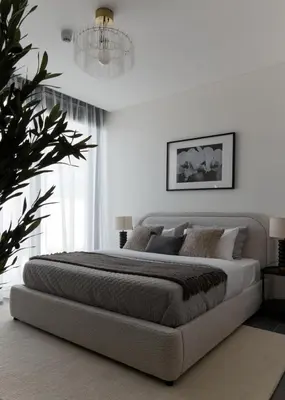 a bedroom with a large bed and a chandelier at Gentle brutalism apartments on Sobha Hartland 3BR in Dubai