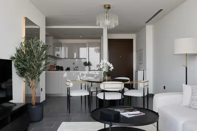 a living room with a table and chairs and a kitchen at Gentle brutalism apartments on Sobha Hartland 3BR in Dubai