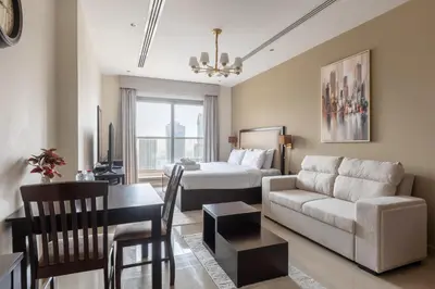 a hotel room with a bed and a living room at Elite Downtown Studio with Balcony & Pool in Dubai