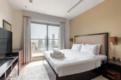 a bedroom with a large bed with a large window at Elite Downtown Studio with Balcony & Pool in Dubai