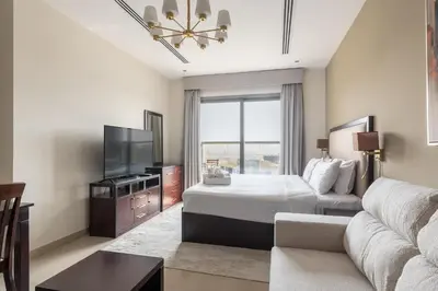 a bedroom with a bed and a tv and a couch at Elite Downtown Studio with Balcony & Pool in Dubai