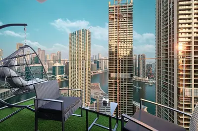 a chair on a balcony with a view of a city at High Rise Premium 2BR apt, PS5, Burj Khalifa view. in Dubai