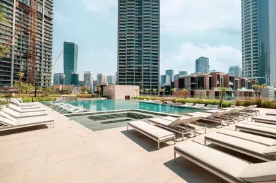 a pool with lounge chairs and a city skyline at High Rise Premium 2BR apt, PS5, Burj Khalifa view. in Dubai
