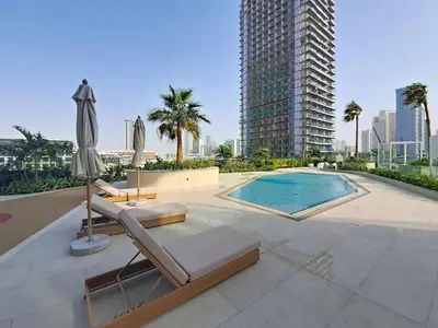 a swimming pool with two lounge chairs and an umbrella at Locations l Aesthetic 1 Bed l Own Private Pool l Circle Mall in Dubai